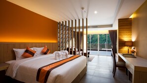 A modern hotel room with a large bed, a desk, and a view of the outdoors. - Balihai Bay (Pattaya)