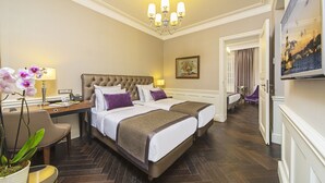 Una habitación de hotel con una cama grande, un escritorio con lámpara, una silla y una planta en maceta.