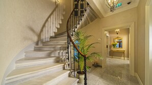 Una escalera de mármol con una planta en maceta, una consola con un espejo y un candelabro.