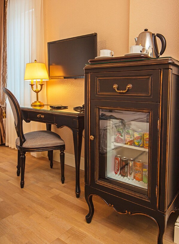 A wooden desk with a lamp, a chair, and a cabinet with a glass door containing beverages. - Meroddi Bagdatliyan Hotel (Istanbul)
