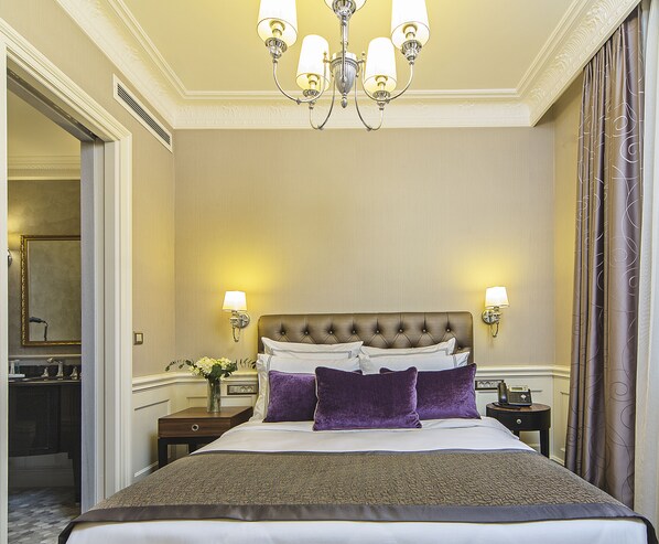 A hotel room with a large bed, two bedside tables, a chandelier, and a mirror on the wall. - Meroddi Bagdatliyan Hotel (Istanbul)
