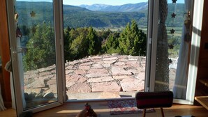 A room with a large sliding glass door leading to a stone patio with a view of a mountainous landscape. - Un Vistón Modern Mountain Home (San Martín de los Andes)