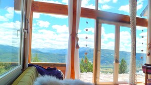 A room with a large window overlooking a mountainous landscape. - Un Vistón Modern Mountain Home (San Martín de los Andes)