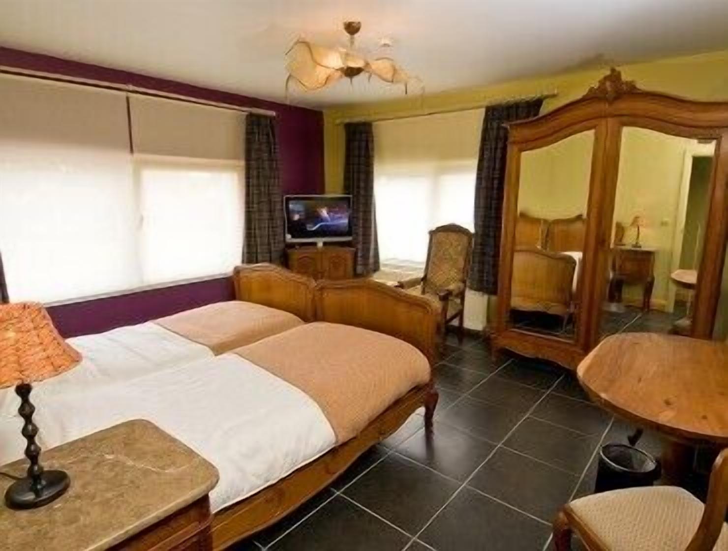 Een hotelkamer met een tweepersoonsbed, een televisie, een spiegel en een klein tafeltje.