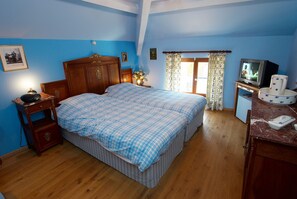 Un dormitorio con una cama grande, cabecera de madera, una mesita de noche, un televisor y una zona de baño con inodoro y lavamanos.