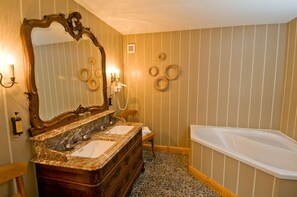 Un baño con tocador de madera, dos lavamanos, un espejo grande, una bañera y detalles decorativos en la pared.