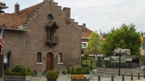 Een gebouw van natuursteen in traditionele stijl, met een centrale toren en rondbogen.