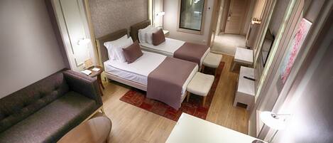 A hotel room with two beds, a sofa, a small table, and a desk.