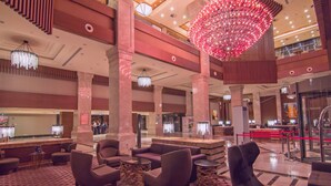 Un vestíbulo amplio con asientos modernos, una lámpara de candelabro grande y una zona de recepción.