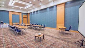 A conference room with a long table, chairs, a projector, and a carpeted floor.