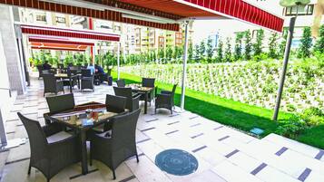 Un espace extérieur aménagé en terrasse, avec des meubles en osier et un auvent rouge.