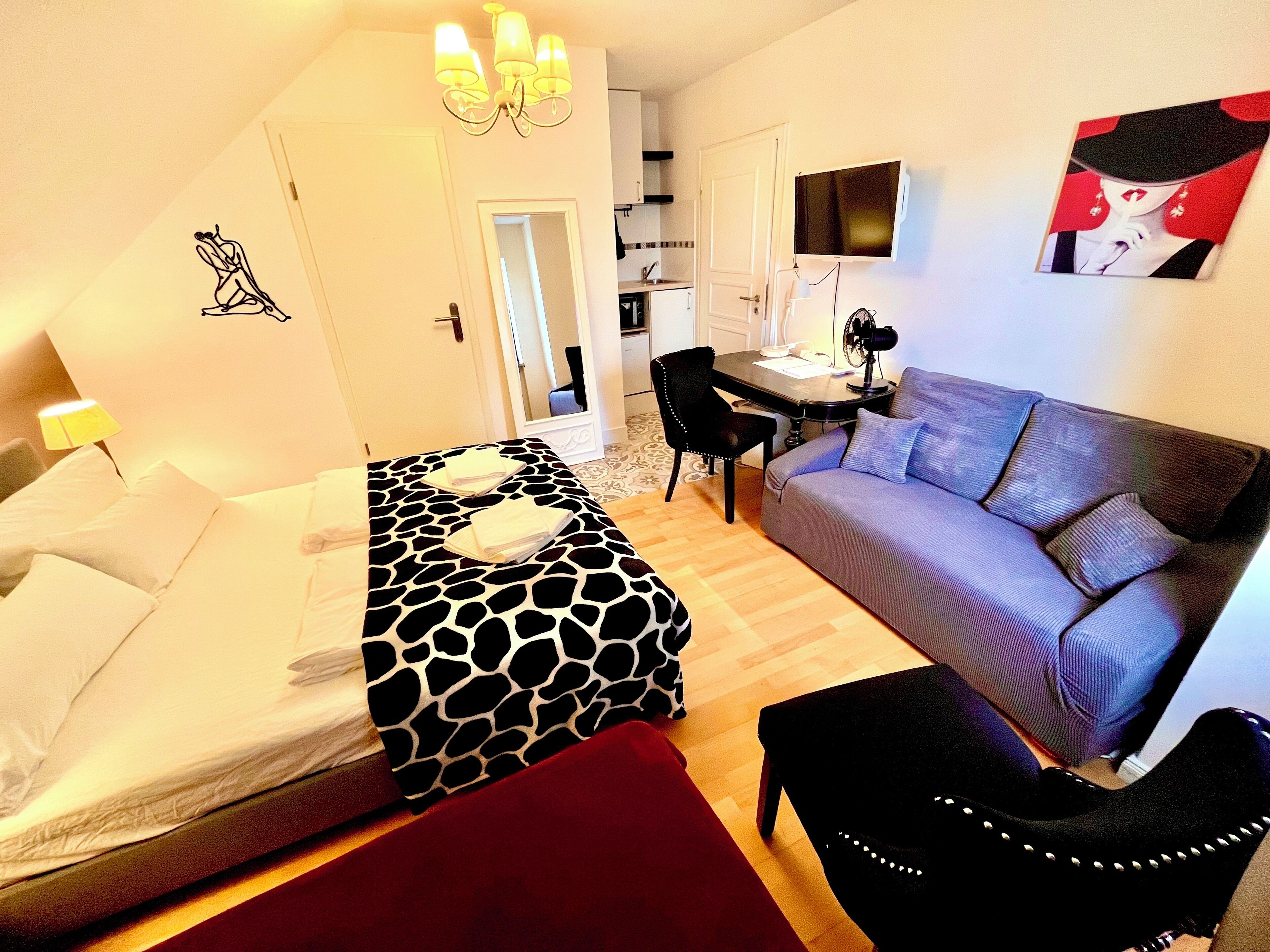 A hotel room with a bed, a sofa, a desk, and a chair.