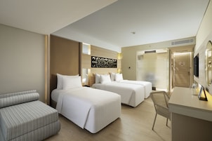 A hotel room with two beds, a desk, a chair, and a large mirror.