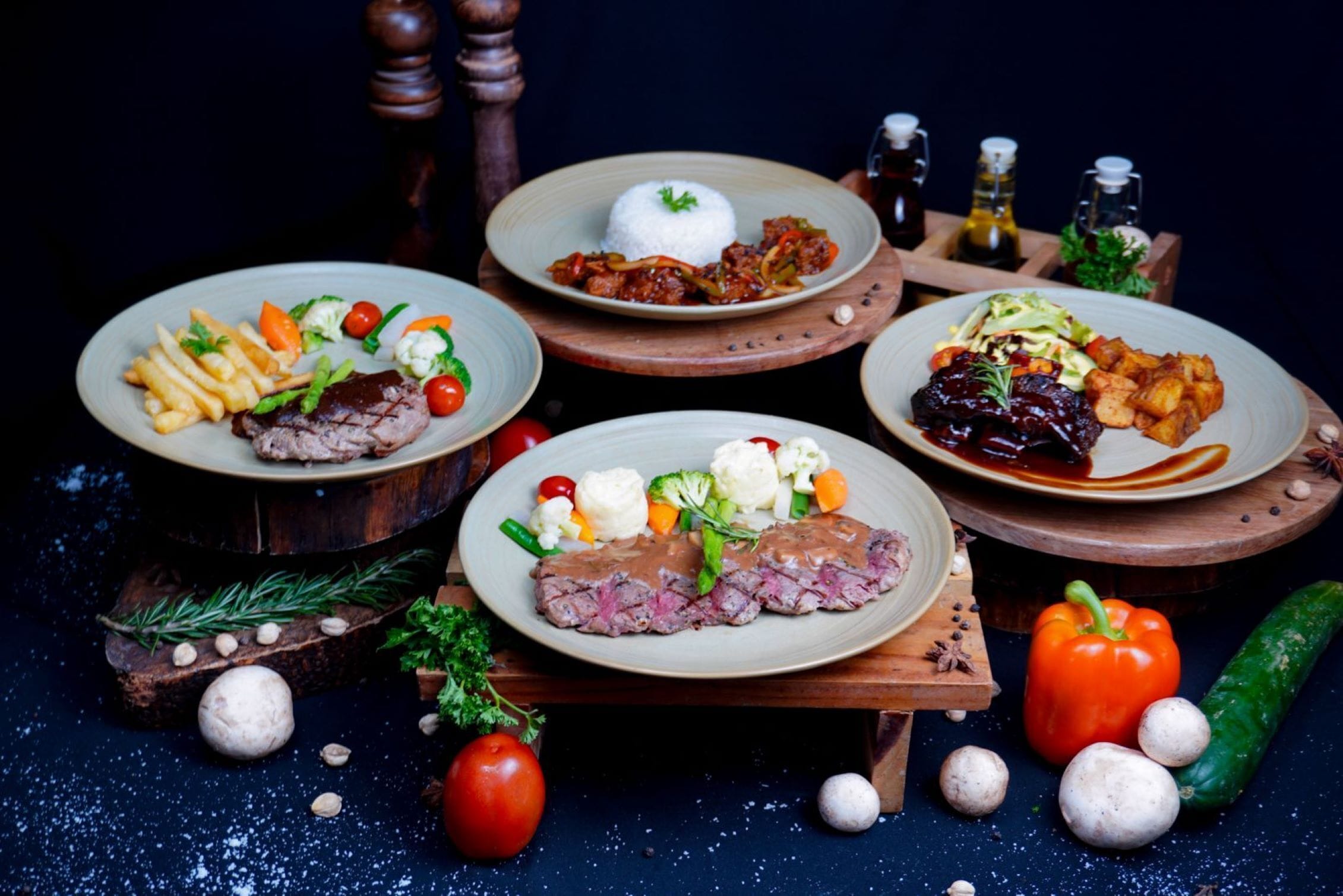 A table with various dishes, including steak, rice, and vegetables, surrounded by condiments and spices.