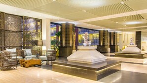 Eine geräumige Lobby mit einer zentralen Sitzecke, einer dekorativen Springbrunnen und einer Treppe zu den oberen Etagen.