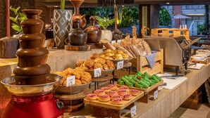 Ein Buffet mit verschiedenen Speisen, darunter Backwaren und Brot, an einem Tresen. Im Hintergrund sind eine Kaffeemaschine und Dekorationen zu sehen.