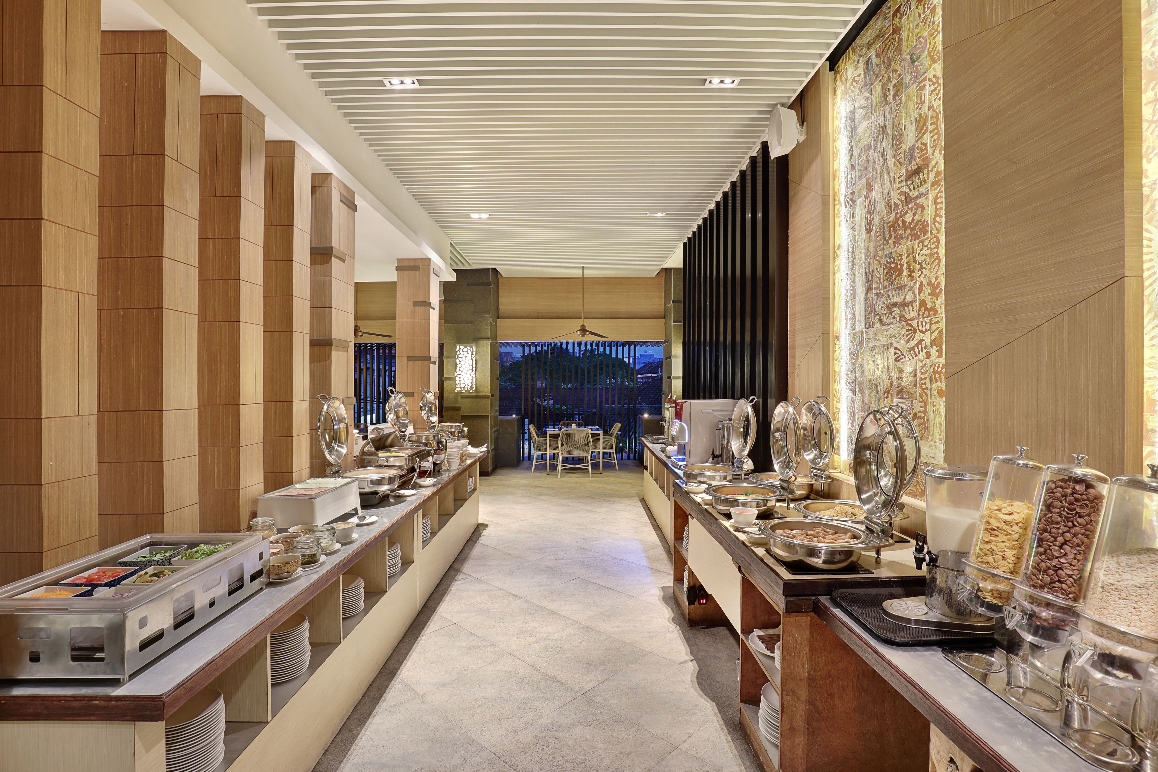 A buffet area with various food stations and a seating area in the background.