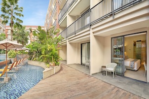 A hotel courtyard with a swimming pool, wooden deck, and lounge chairs.