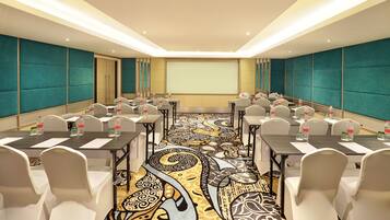 A conference room with a large screen, multiple tables, and chairs arranged for meetings.