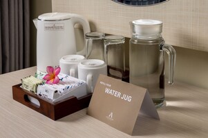 A hotel room with a coffee maker, water jugs, and a card indicating the room's amenities.