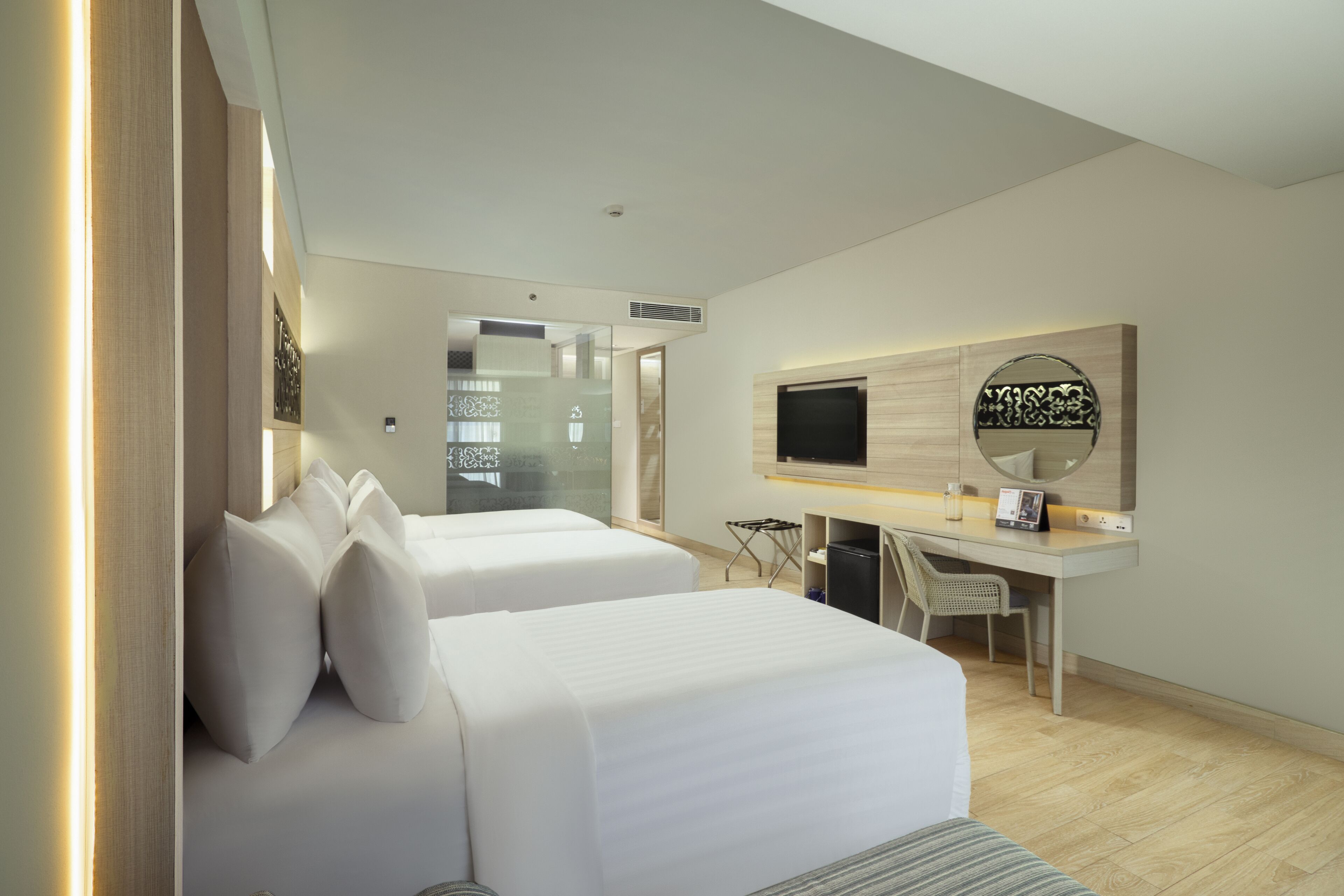 A modern hotel room with two beds, a desk, a TV, and a mirror.