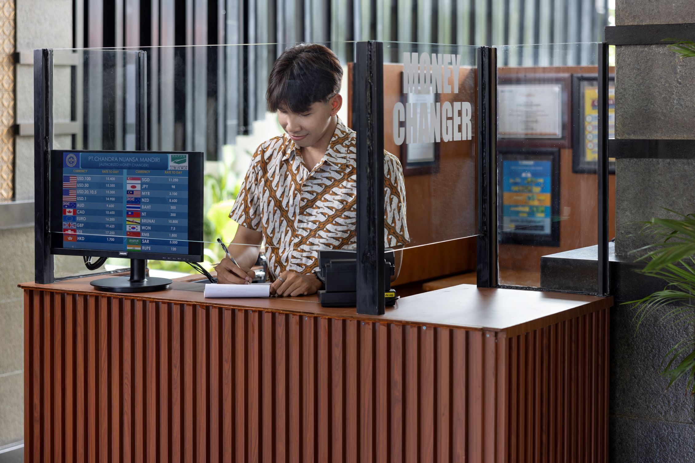 A reception desk with a computer monitor displaying currency exchange rates.