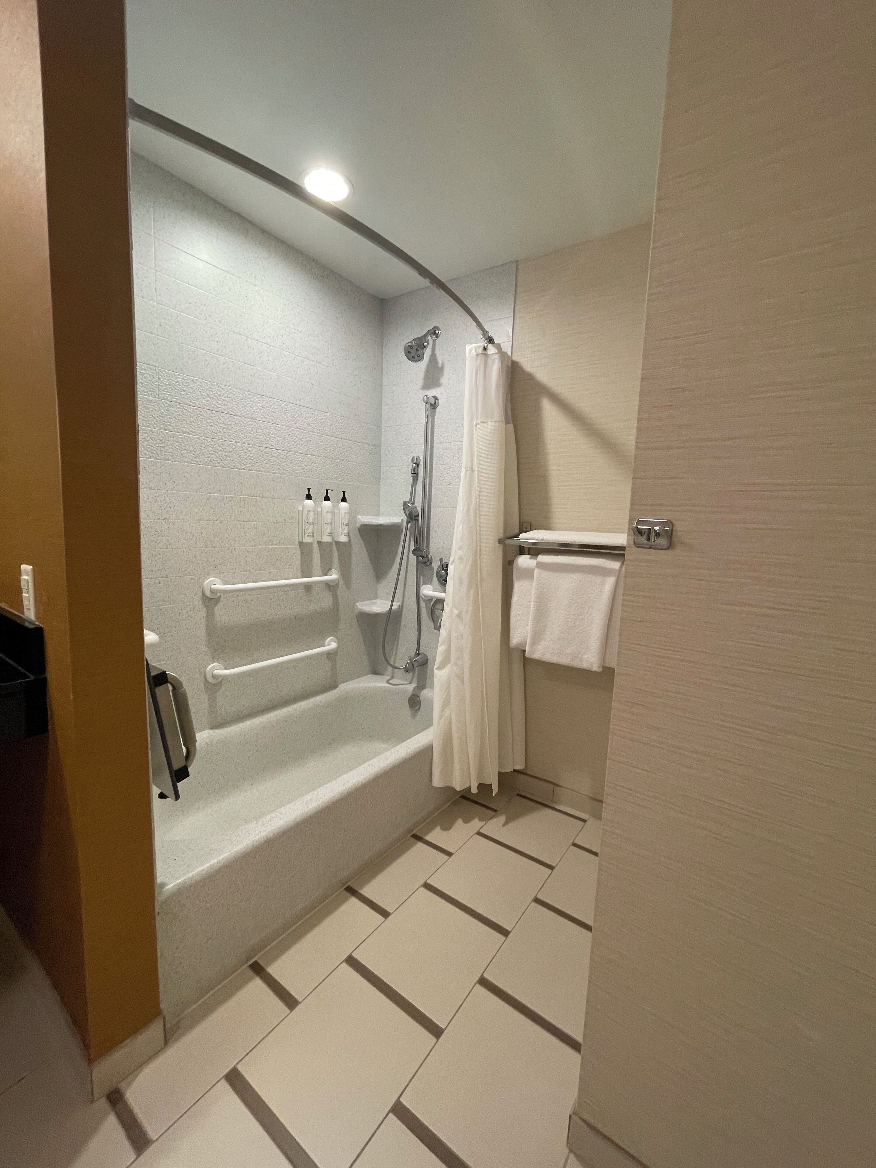 A modern bathroom with a bathtub, shower, and toilet.