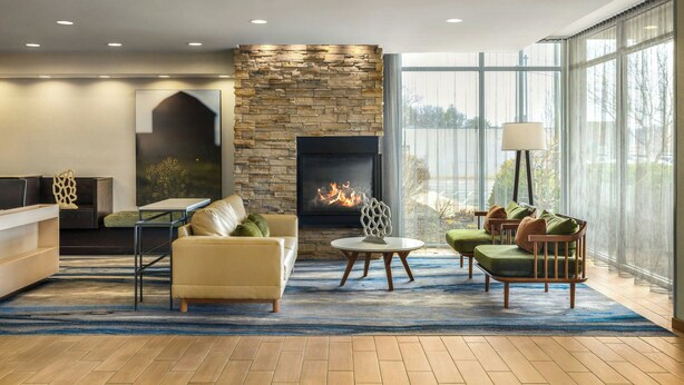 A modern living room with a fireplace, comfortable seating, and large windows. - Fairfield Inn & Suites Athens (Athens)