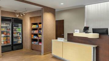 A hotel reception area with a reception desk, a minibar, and a refrigerator stocked with snacks and beverages.