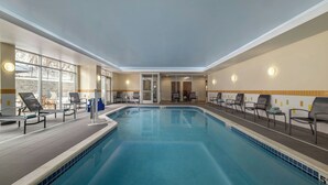 An indoor swimming pool with lounge chairs, a tiled floor, and a view through the glass doors. - Fairfield Inn & Suites Athens (Athens)