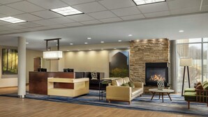 A modern lobby with a reception desk, seating area, fireplace, and large windows. - Fairfield Inn & Suites Athens (Athens)