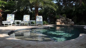En swimmingpool med liggestole og et lille vandfald.
