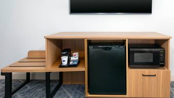 A compact kitchenette with a microwave, coffee maker, and storage for coffee pods.