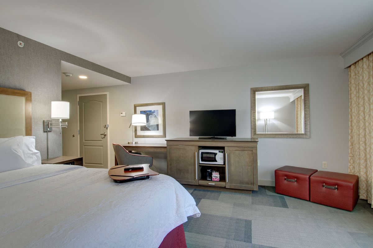 A hotel room with a bed, a television, a microwave, a desk, and a wardrobe.