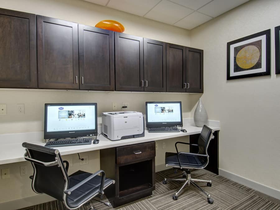 A conference room with two desktop computers, a printer, and two office chairs.
