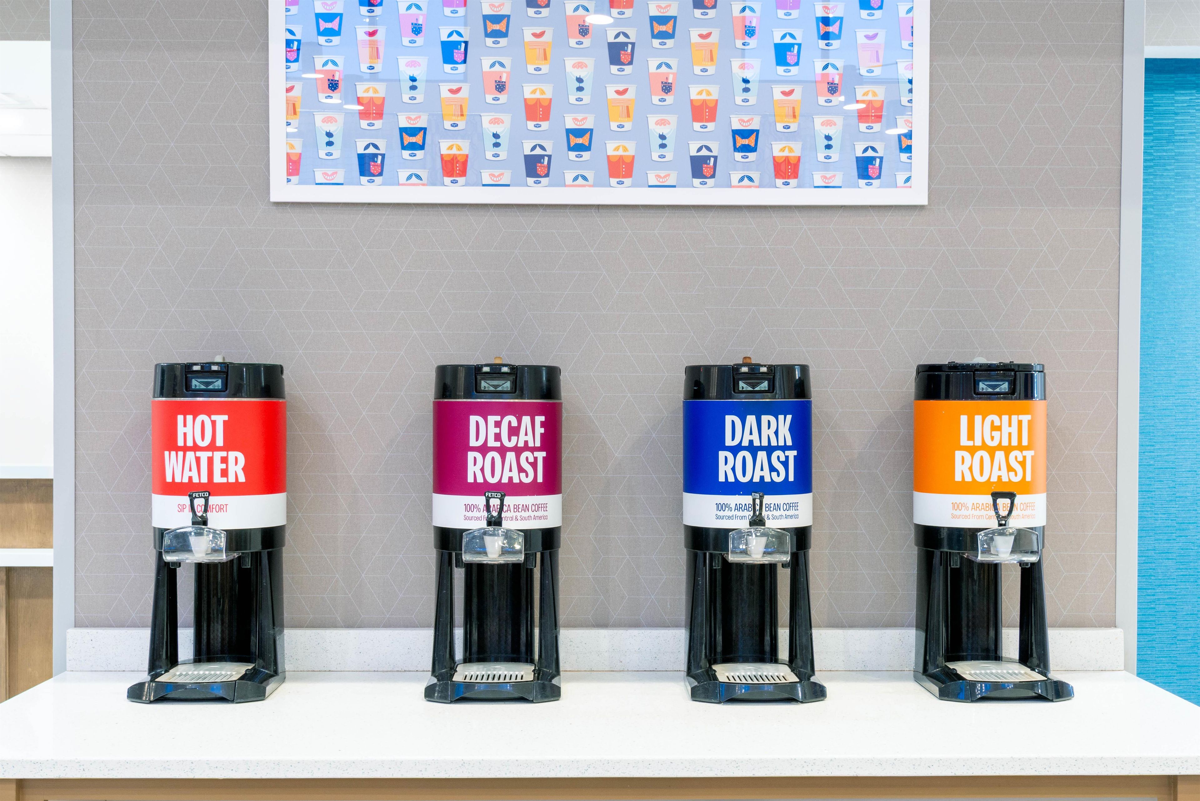Cuatro dispensadores de café con las etiquetas 'AGUA CALIENTE', 'CAFÉ DESCAFEINADO', 'CAFE FUERTE' y 'CAFE CLARO' sobre una encimera.