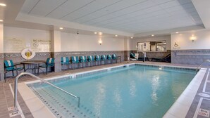 Una piscina interior con socorrista, sillas de piscina y elevador para piscina.