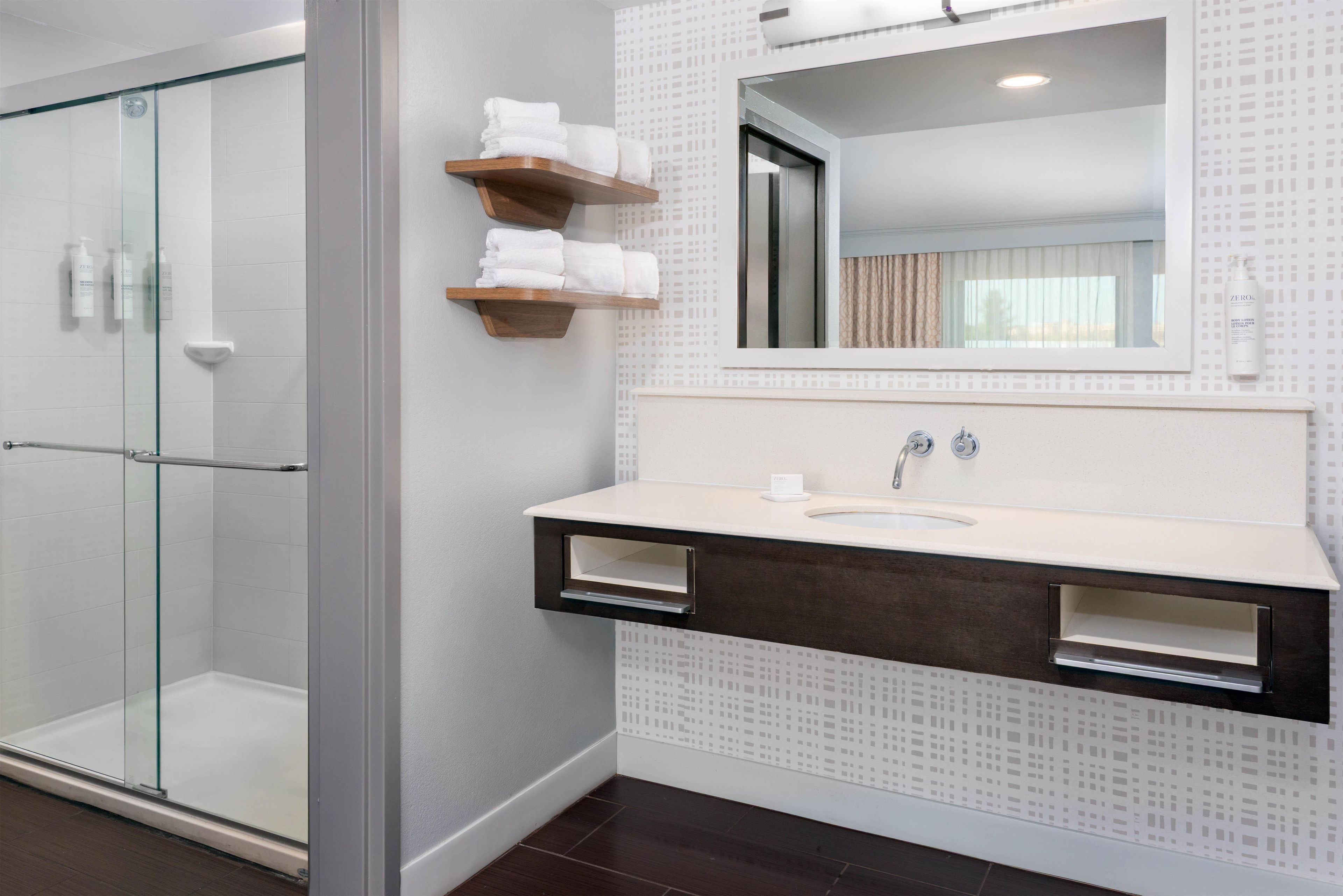 Une salle de bain moderne avec une douche à parois de verre, un meuble-lavabo avec un miroir et un évier.