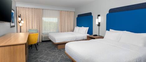A hotel room with two beds, a desk, a chair, a TV, and a window with curtains.