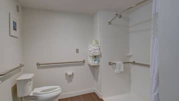 A bathroom with a toilet, a shower with a grab bar, and a towel rack.
