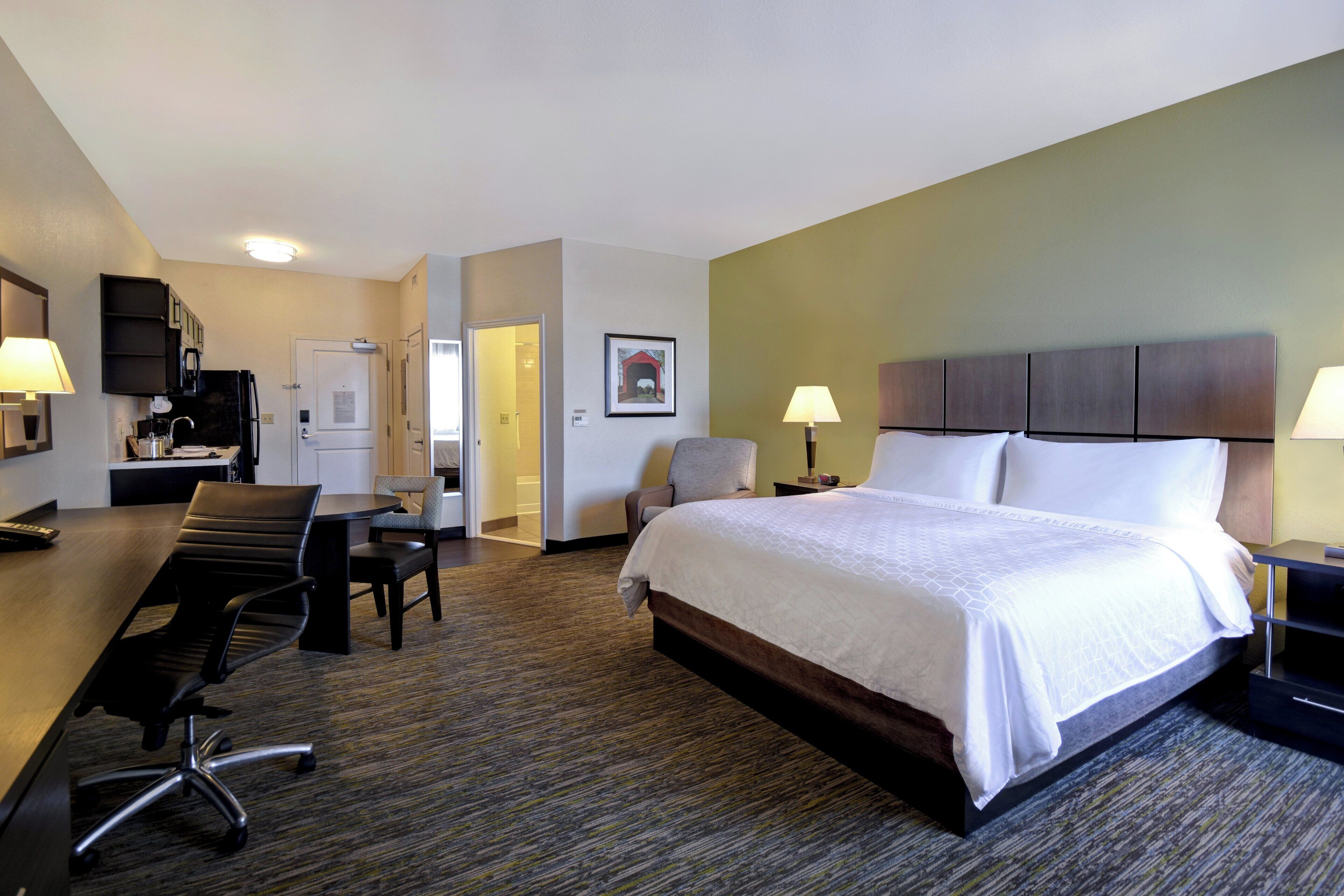 Una habitación de hotel con cama, escritorio, sillas y televisión.