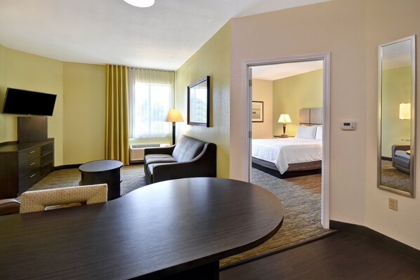 A hotel room with a bed, a desk, a chair, a TV, and a lamp. - Candlewood Suites St. Clairsville by IHG (St. Clairsville)