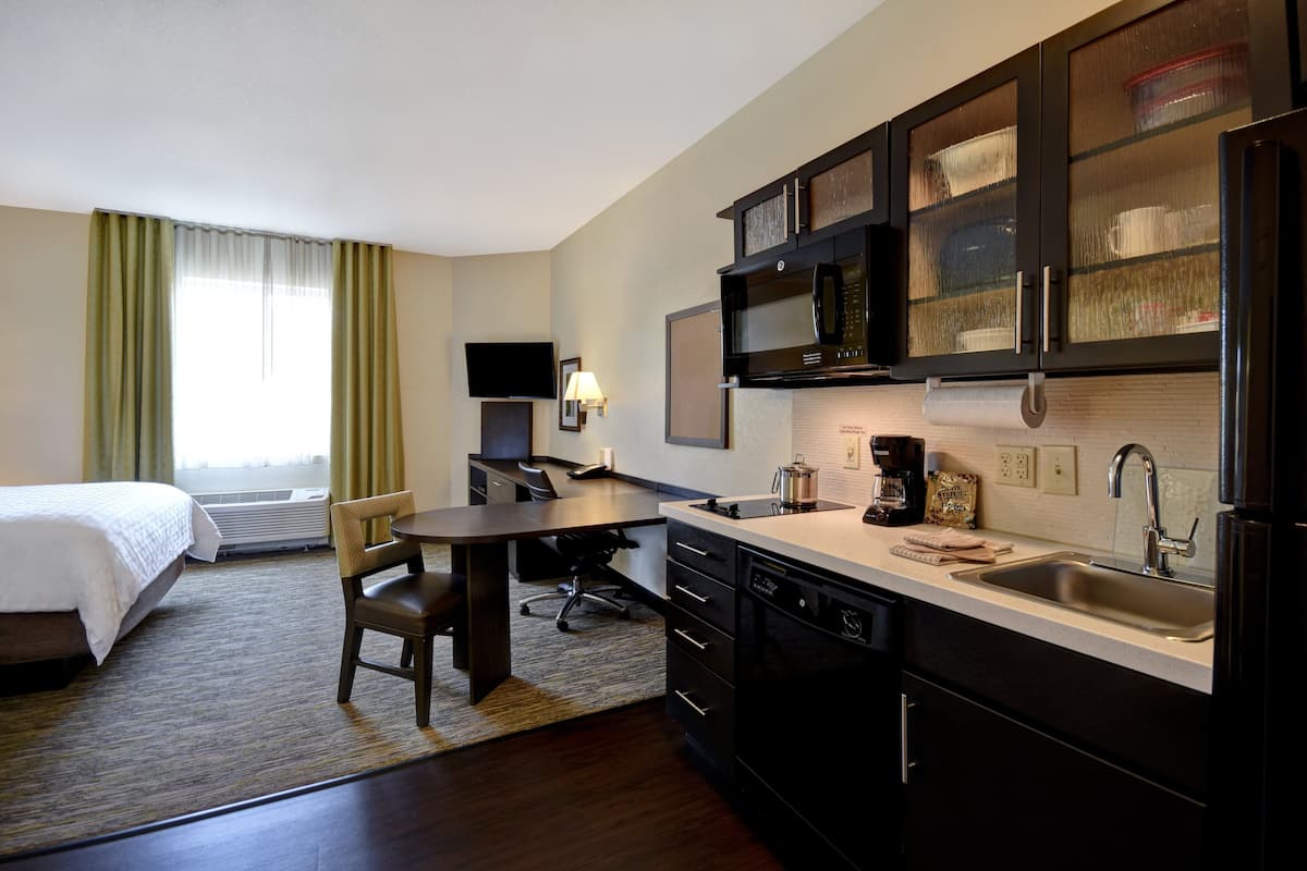 Une chambre d’hôtel équipée d’un lit, d’un bureau, d’une chaise, d’une kitchenette et d’un téléviseur.