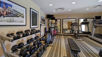 A gym with various exercise equipment, including dumbbells, a treadmill, and a stationary bike.