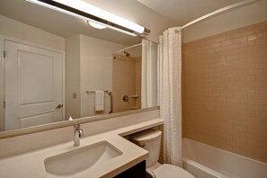 A bathroom with a sink, mirror, toilet, and shower. - Candlewood Suites St. Clairsville by IHG (St. Clairsville)