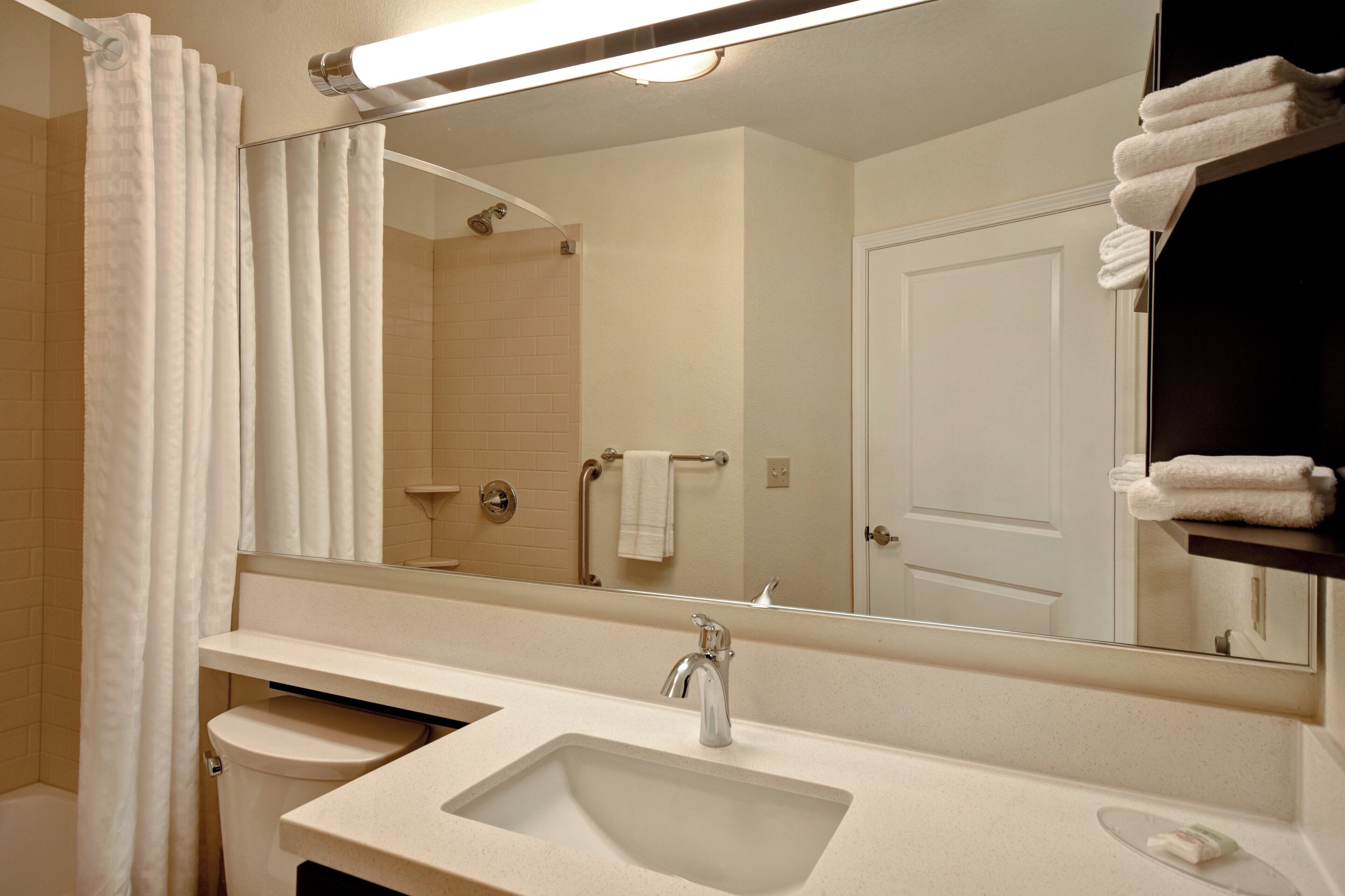A bathroom with a sink, mirror, and towel rack.