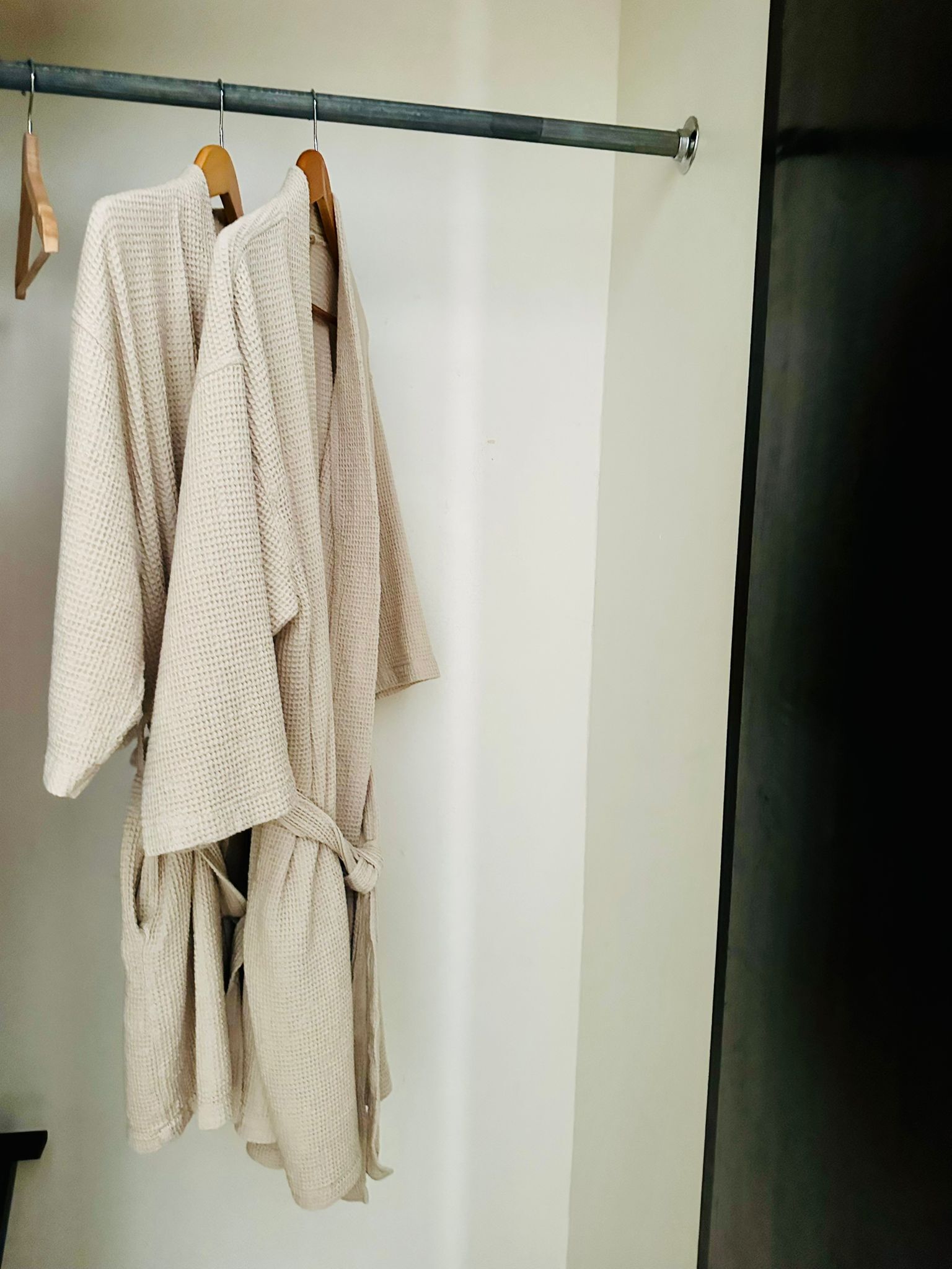 A clothing rack with several light-colored robes hanging.