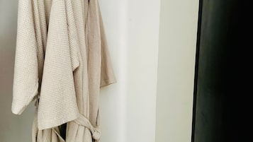 A clothing rack with several light-colored robes hanging.