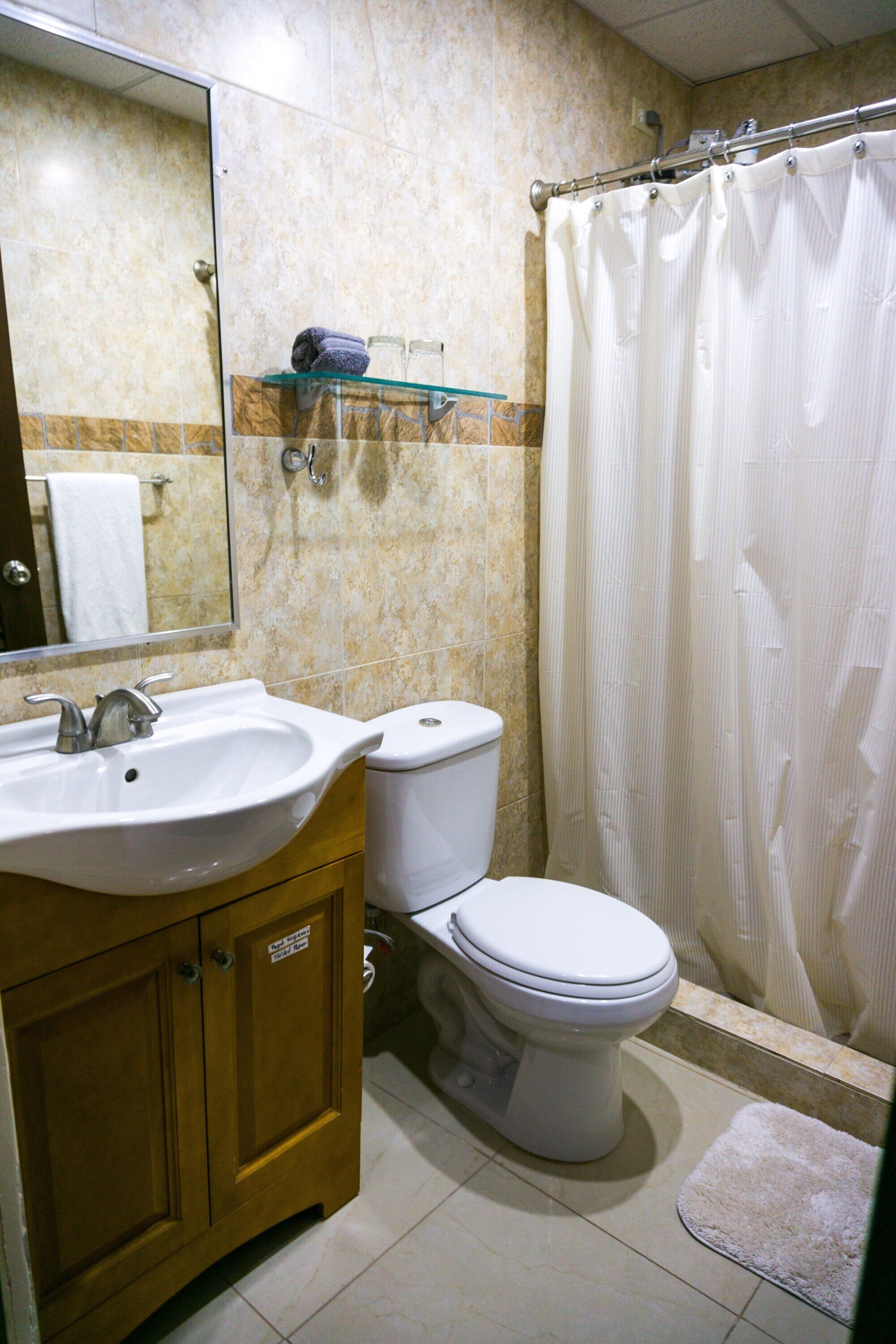 A bathroom with a sink, toilet, and shower curtain.