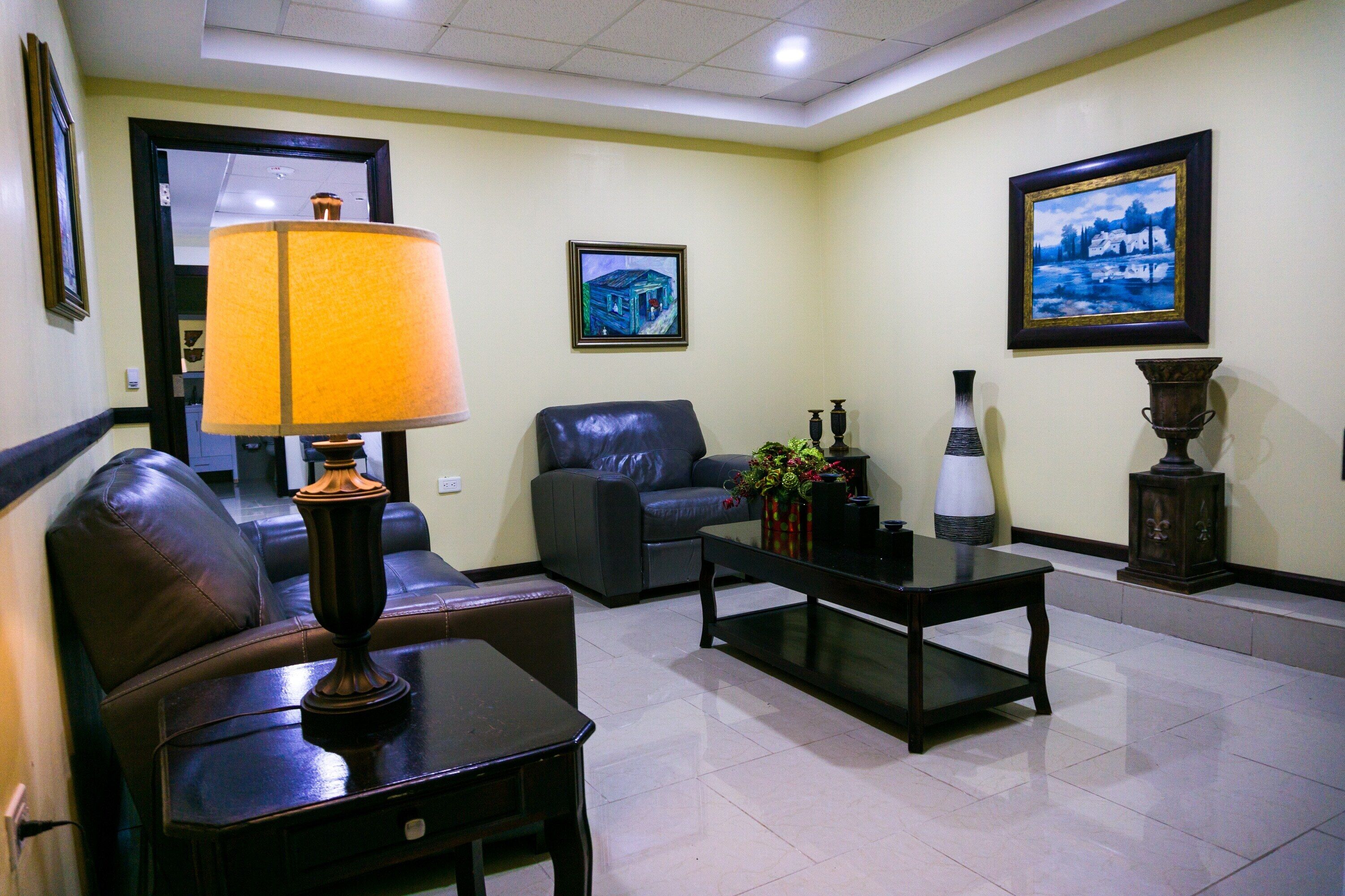 A living room with a sofa, a coffee table, a lamp, and two paintings on the wall.